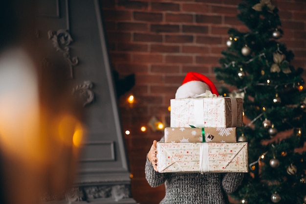 Mujer, con, presentes, posición, delante de, árbol de navidad