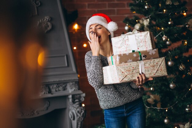 Mujer, con, presentes, posición, delante de, árbol de navidad