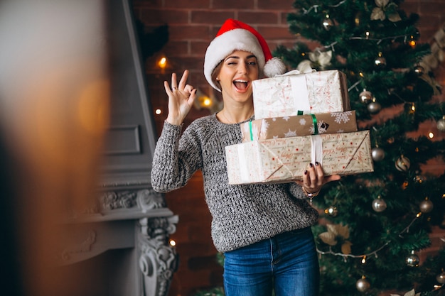 Mujer, con, presentes, posición, delante de, árbol de navidad