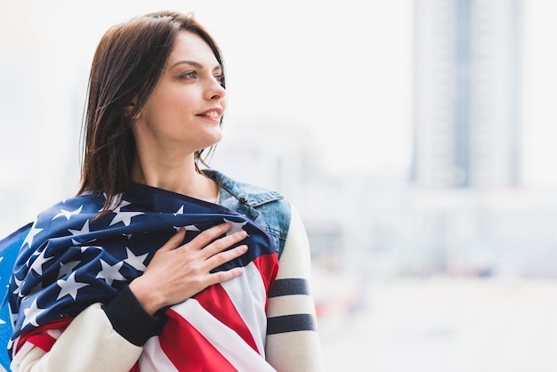 Mujer presionando la bandera americana al corazón