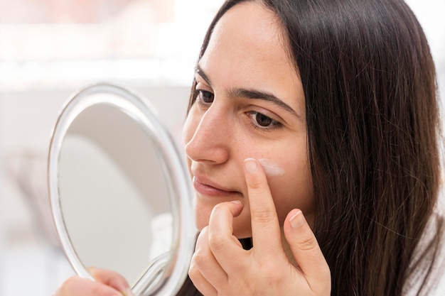 Mujer de primer plano aplicar crema facial