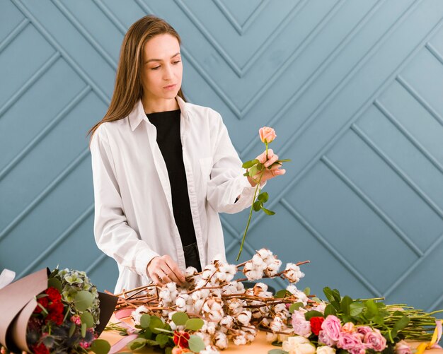 Mujer de primer plano con bata blanca sosteniendo una flor