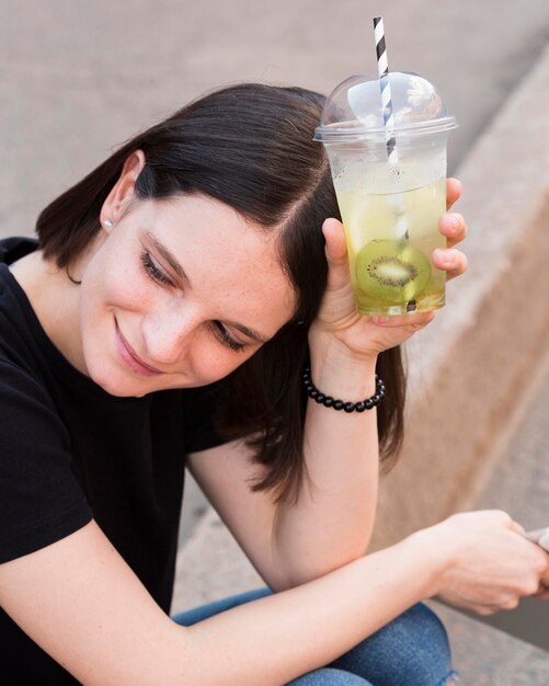 Mujer de primer plano con bebida de kiwi
