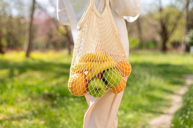 Foto gratuita mujer de primer plano con bolsa reutilizable caminando afuera