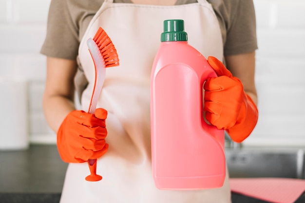 Mujer de primer plano con botella de detergente