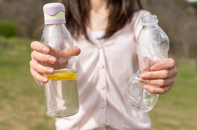 Mujer de primer plano con botellas de vidrio y plástico