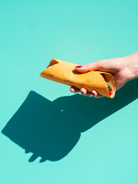 Mujer de primer plano con burrito y fondo azul
