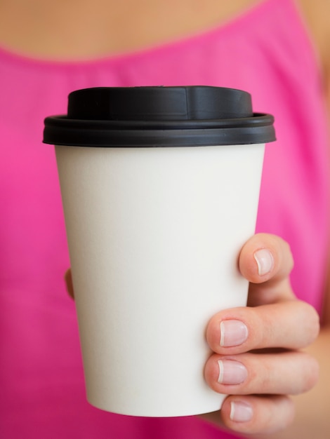 Mujer de primer plano con camisa rosa y taza de café