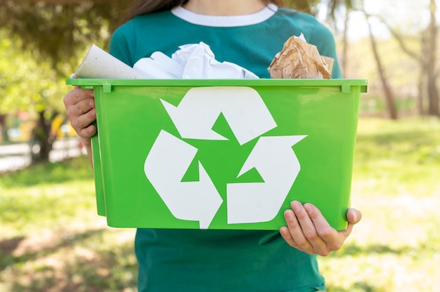 Mujer de primer plano con cesta de reciclaje en la naturaleza