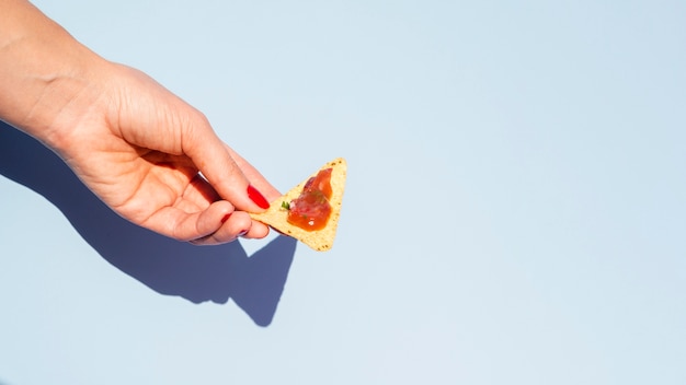 Mujer de primer plano con chips de tortilla y fondo azul.