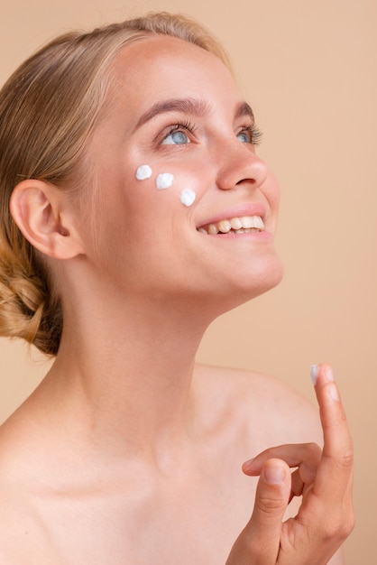 Mujer de primer plano con crema para la cara mirando hacia arriba