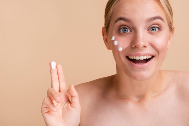 Mujer de primer plano con crema para la cara se sorprende