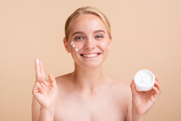 Mujer de primer plano con crema para la cara y tarro