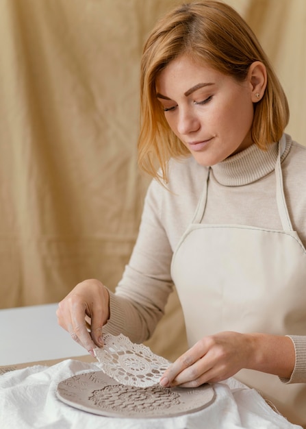 Mujer de primer plano decorar plato de arcilla