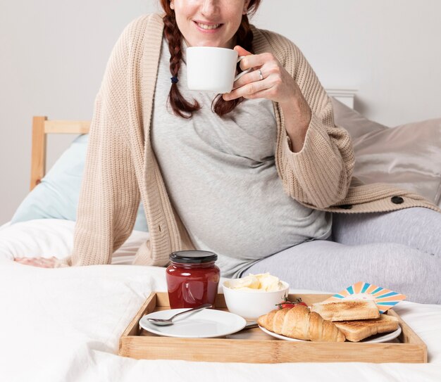 Mujer de primer plano disfrutando de brunch en la cama