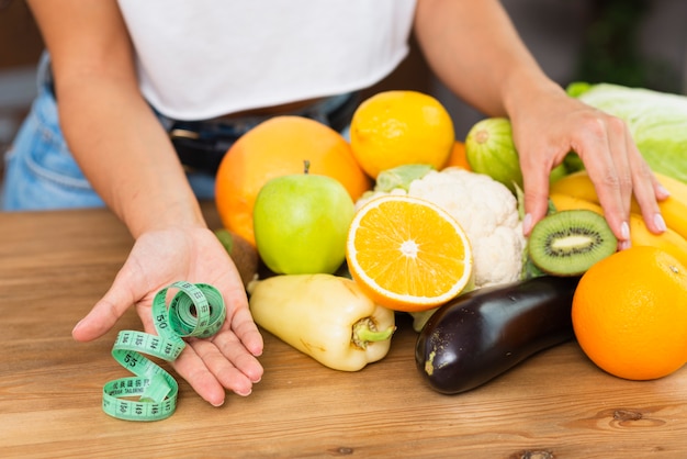 Mujer de primer plano con frutas y cinta métrica