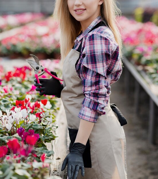 Mujer de primer plano en invernadero con tijera de jardinería