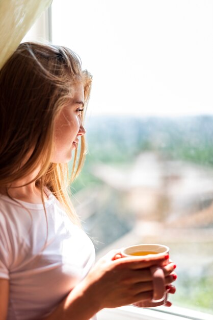 Mujer de primer plano mirando por la ventana