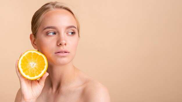 Mujer de primer plano con naranja mirando a otro lado