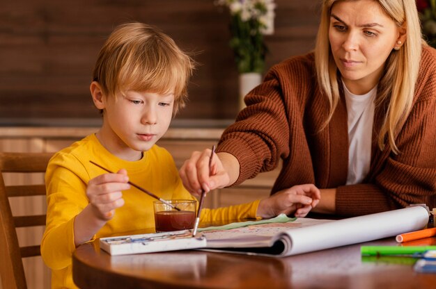 Mujer de primer plano y niño con acuarelas