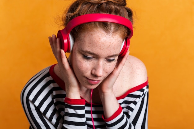 Mujer de primer plano con pecas y auriculares rojos