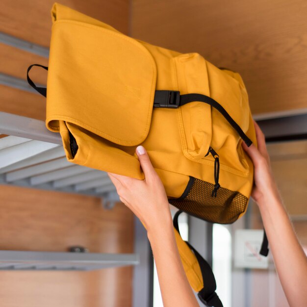 Mujer de primer plano poniendo mochila en la rejilla del tren