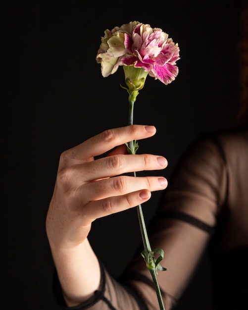 Mujer de primer plano sosteniendo una flor