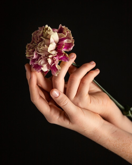 Mujer de primer plano sosteniendo una flor