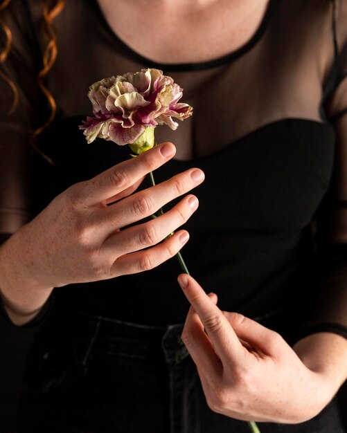 Mujer de primer plano sosteniendo una flor