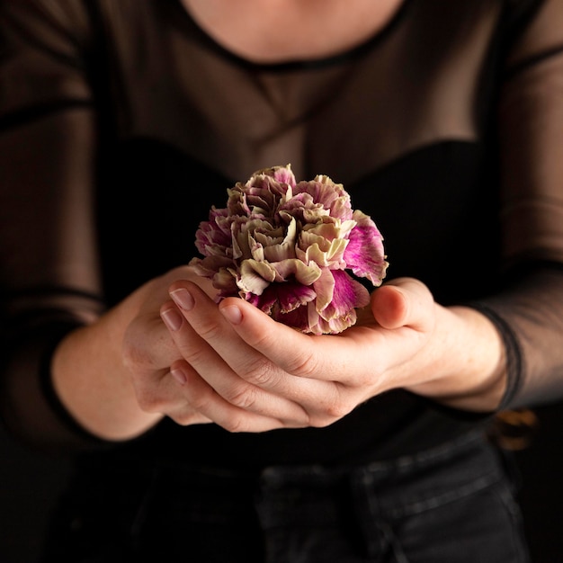 Mujer de primer plano sosteniendo una flor