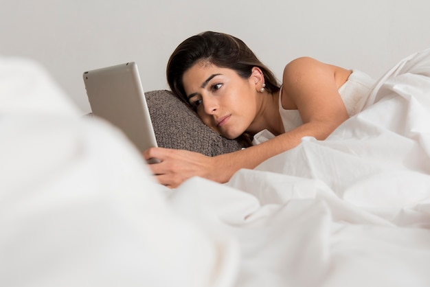 Mujer de primer plano con tableta en la cama