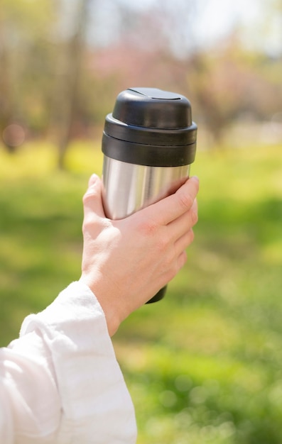 Mujer de primer plano con termo en la naturaleza