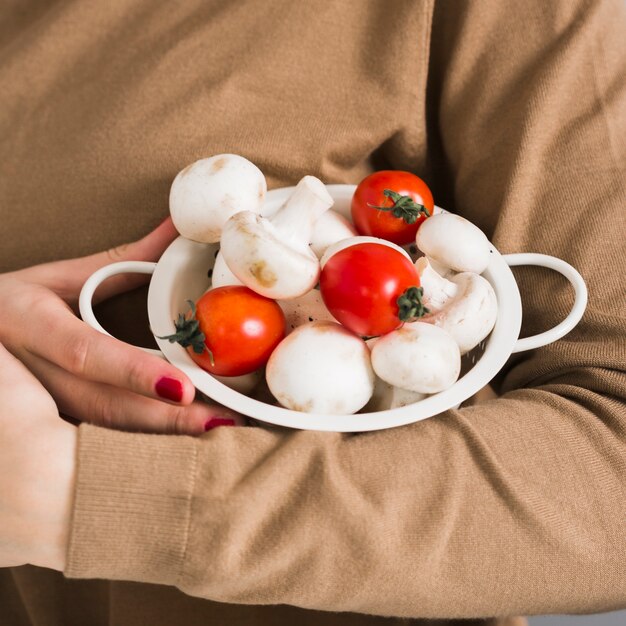 Mujer de primer plano con tomates y champiñones orgánicos