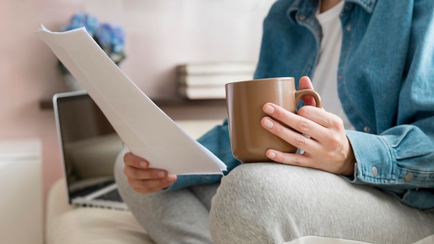 Mujer de primer plano trabajando en sofá y tomando café