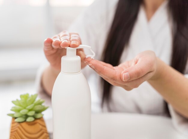 Mujer de primer plano vertiendo crema de manos