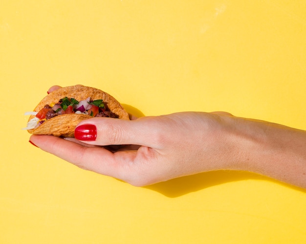 Mujer del primer que sostiene el taco con el fondo amarillo