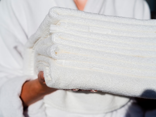 Mujer del primer que sostiene las toallas limpias dobladas blanco