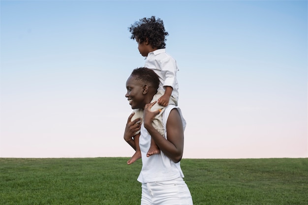 Foto gratuita mujer, proceso de llevar, niño, en, hombros, vista lateral