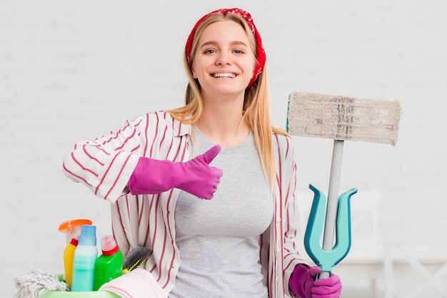 Mujer con productos de limpieza que muestra signo ok