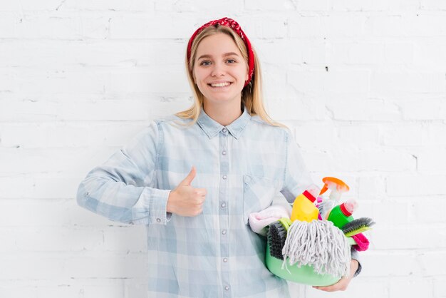 Mujer con productos de limpieza que muestra signo ok