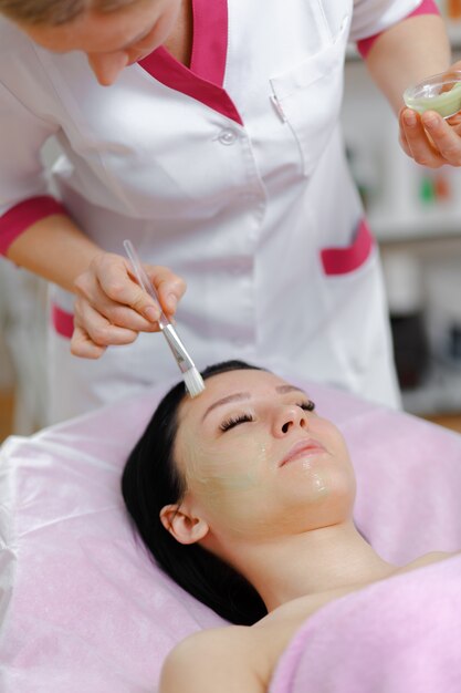 Mujer profesional aplicando una crema verde con un pincel