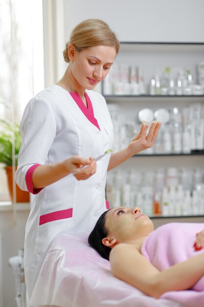 Mujer profesional aplicando una crema verde con un pincel