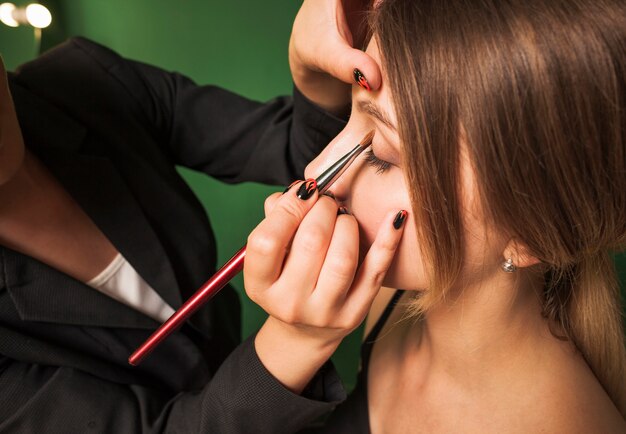 Mujer profesional maquillando ojos de una chica