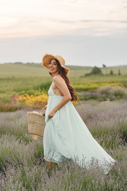 Mujer provenzal relajante en campo de lavanda. Dama con sombrero de paja. Chica con bolso.