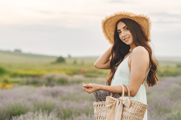 Mujer provenzal relajante en campo de lavanda. Dama con sombrero de paja. Chica con bolso.