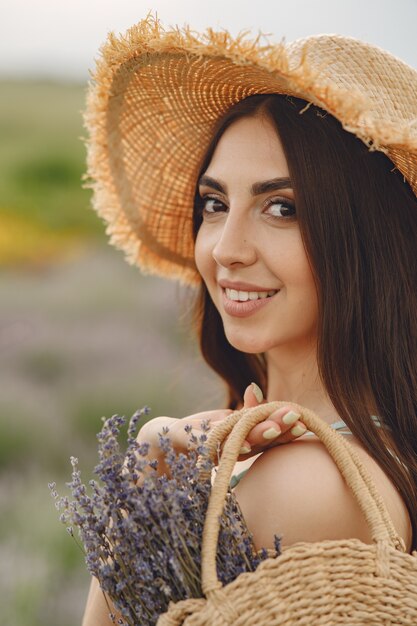 Mujer provenzal relajante en campo de lavanda. Dama con sombrero de paja. Chica con bolso.