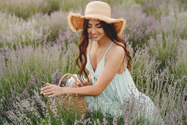 Mujer provenzal relajante en campo de lavanda. Dama con sombrero de paja. Chica con bolso.