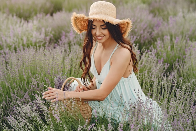 Mujer provenzal relajante en campo de lavanda. Dama con sombrero de paja. Chica con bolso.