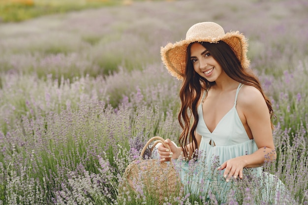 Mujer provenzal relajante en campo de lavanda. Dama con sombrero de paja. Chica con bolso.