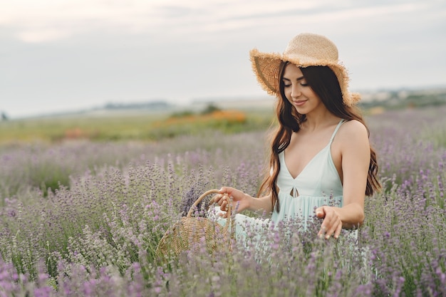 Mujer provenzal relajante en campo de lavanda. Dama con sombrero de paja. Chica con bolso.